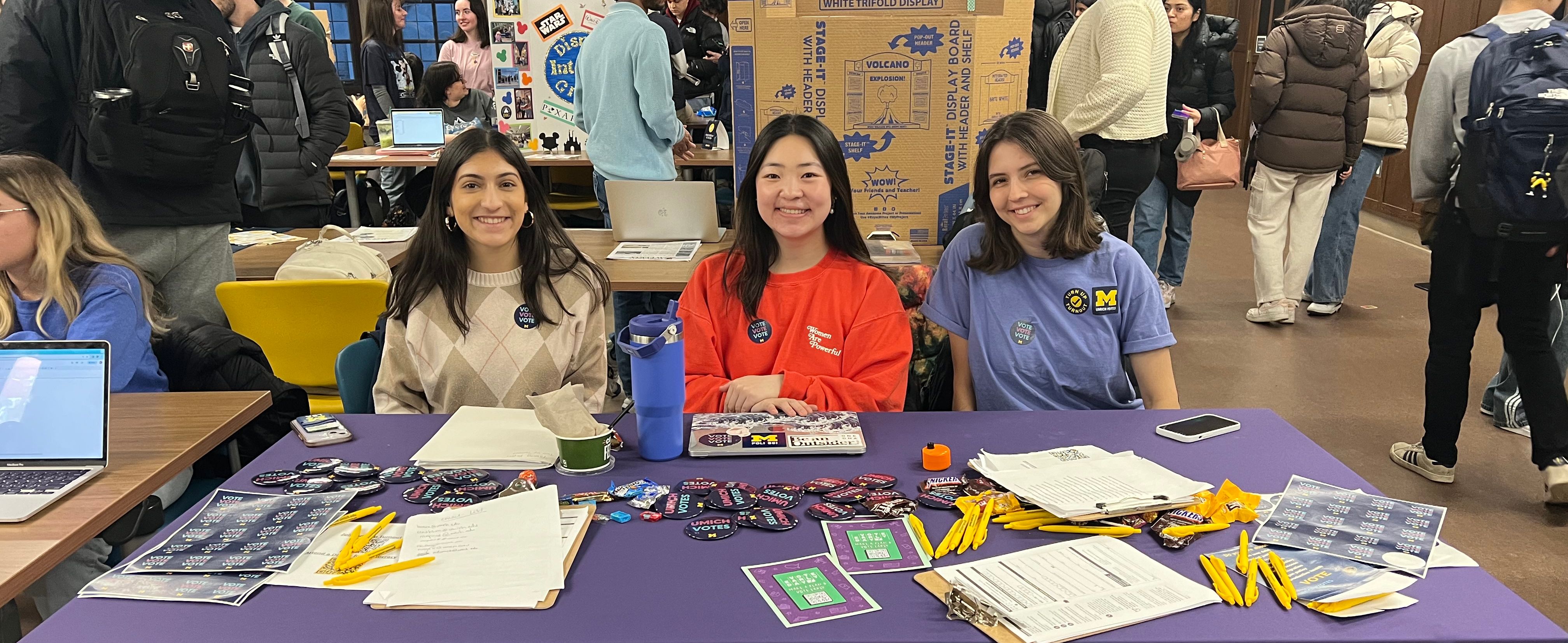 Student volunteers working a Umich Votes table at an indoor event